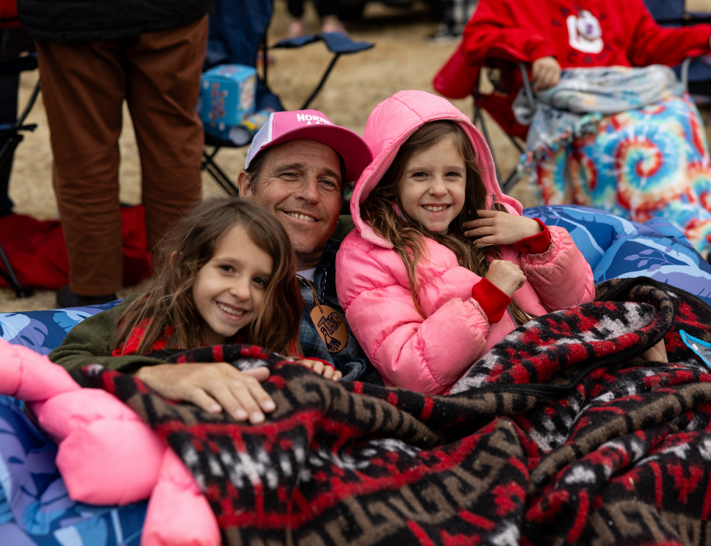 A dad and his twin daughters outside